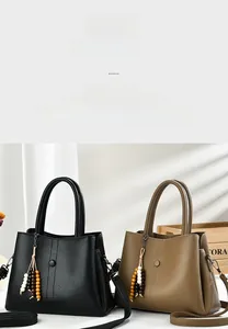 Detail view of stylish pebbled leather handbags in black and khaki with bead tassel charms