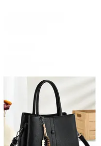 Detail of black pebble leather tote bag with elegant beaded tassel and adjustable strap