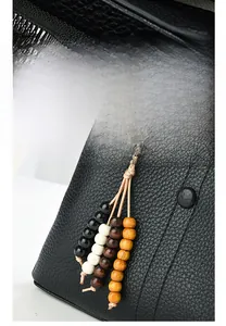 Detail of black lychee grain leather handbag with colorful beaded strap accessory