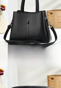 Rear view of black pebble leather handbag with removable strap and round decorative button