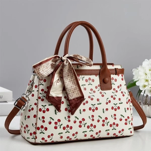 Classic cream tote bag with red cherry print and brown leather handles and strap