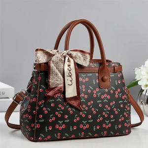 Detail of black leather tote bag with cherry print, brown handles and decorative silk scarf