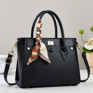 Classic black leather tote bag with silk scarf accent and gold twist lock on display