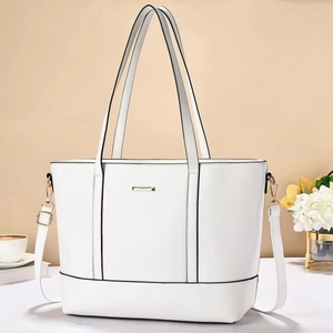 Detail of white tote bag with structured design, gold hardware and adjustable strap