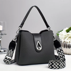 Deep grey textured handbag with black leather flap and geometric patterned wide shoulder strap