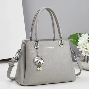 Detail of grey lychee leather handbag with seashell pendant and fashion text engraving