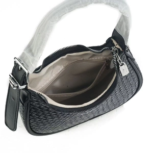 Detail view of woven black underarm bag featuring silver zipper and beige inner lining