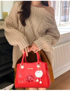 Detail of red embroidered floral handbag for middle-aged women with plush ball charm