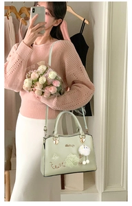 Pale green PU leather handbag featuring floral embroidery and a white pompom charm detail