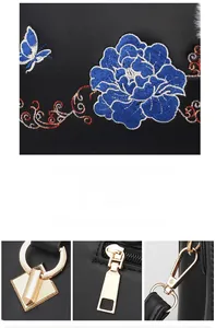 Detailed close-up of intricate peony floral embroidery and golden metal hardware on black bag