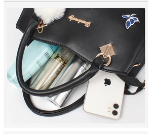 Detail of black leather handbag featuring floral butterfly embroidery and spacious interior