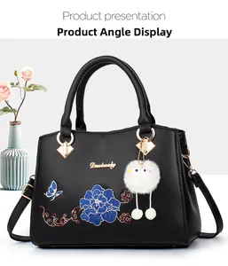 Detail showing blue floral embroidery and gold hardware on black leather handbag