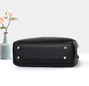 Detail view of the black leather handbag bottom featuring four gold metal protective studs
