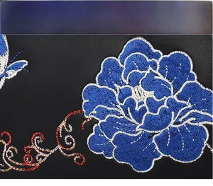 Detailed close-up of intricate blue peony embroidery and butterfly on black handbag