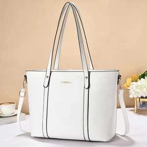 Detail view of large white tote bag with golden metal trim and adjustable shoulder strap