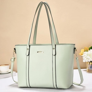 Detail of light green tote bag featuring high-quality leather texture and gold hardware