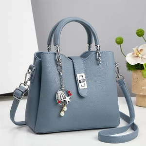 Detail of blue lychee leather handbag with silver twist lock and ocean themed charm