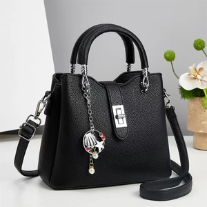 Detail of black pebbled leather handbag with silver twist lock and nautical charms