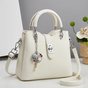Detail of off-white leather handbag showing metal twist lock and sea-themed charms