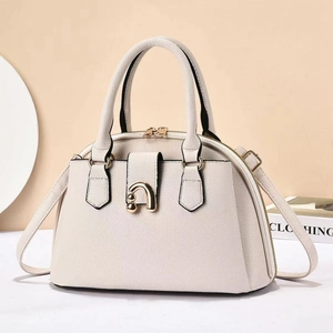 Detailed macro view of cream tote bag featuring lychee texture and gold metal buckle