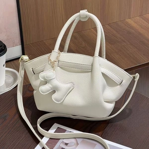 Close-up of white lychee pattern leather handbag with cute puppy charm and gold hardware
