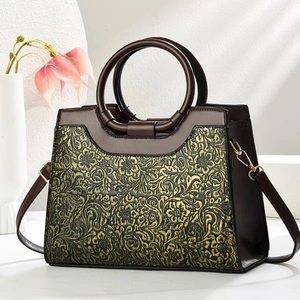 Close-up of vintage floral embossed pattern on dark brown leather shoulder bag detail