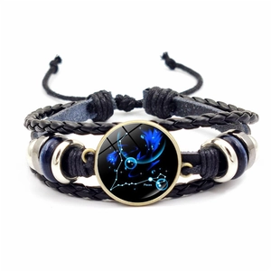 Détail macro du bracelet multicouche en cuir tressé signe Poissons avec cabochon en verre