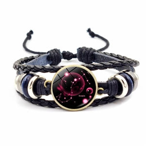 Gros plan d'un bracelet en cuir tressé noir avec breloque en verre du signe du Scorpion
