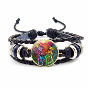 Macro detail of multilayer woven leather bracelet with dreamcatcher and dragonfly glass dome