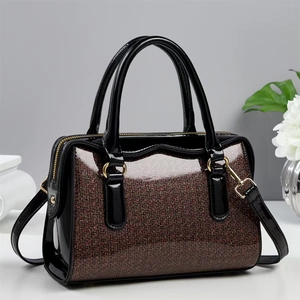 Chic black patent leather Boston bag with shimmering stone texture and gold accents