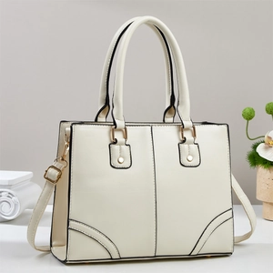Close-up of minimalist cream tote bag with gold hardware and protective bottom studs