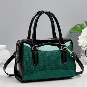 Close-up of green sequin handbag detailing with golden zippers and black patent leather
