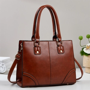 Detail of retro brown PU leather tote bag with gold rivets and adjustable shoulder strap