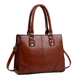 Brown leather tote bag with gold hardware and adjustable strap on white background