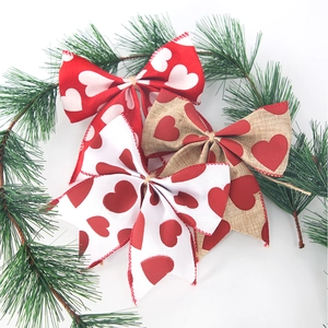 Detailed view of three heart-print burlap bows arranged with festive pine branches decor