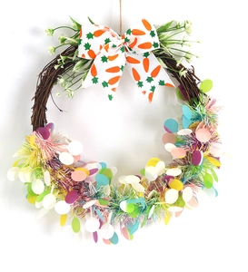 Detail of Easter wreath featuring carrot bow, white flowers and colorful sequins on vine