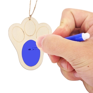 Detail of hand painting a blue pattern on a wooden foot-shaped DIY craft pendant