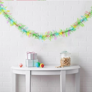 Detail of colorful Easter tinsel garland with pastel egg discs hanging on a white brick wall