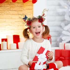 Close-up of golden reindeer antlers headband with red roses and festive berries decor