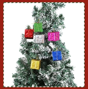 Gros plan de mini boîtes cadeaux étincelantes colorées suspendues sur un sapin de Noël enneigé