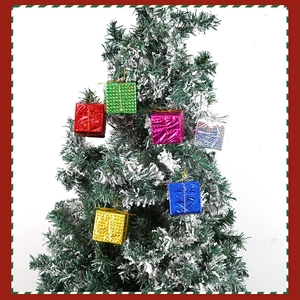 Mini boîtes cadeaux scintillantes colorées suspendues sur une branche enneigée