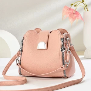 Detail of pink pebbled leather bucket bag with silver metal buckle and elegant chain strap