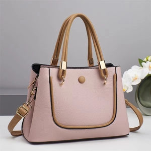 Pink lychee texture handbag with brown handles and golden hardware in elegant setting