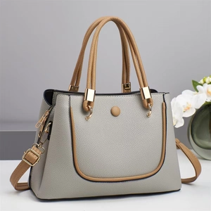 Detail of color-block tote bag featuring grey and brown pebble leather with gold hardware