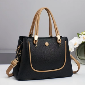 Detail of black pebbled leather handbag with contrast khaki trim and gold hardware