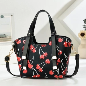 Detailed view of black dumpling bag with red cherry print and golden metal hardware