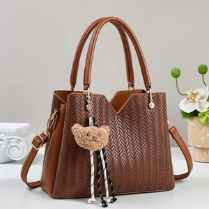 Détail d'un sac cabas marron tissé avec bandoulière réglable et pendentif ours en peluche