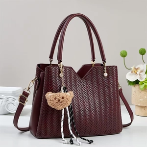 Sac cabas tressé bordeaux avec poignées et breloque ours en peluche sur fond minimaliste