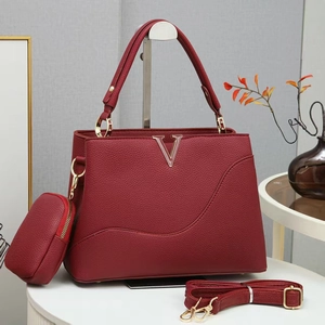 Détail de la texture cuir rouge vin et logo en V doré sur le sac à main de luxe