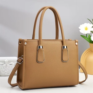 Minimalist caramel brown pebbled leather handbag with silver buckles and crossbody strap